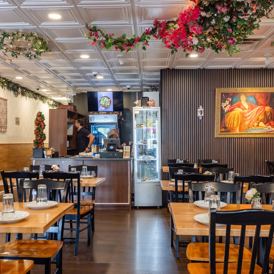Inviting restaurant dining room with set tables, floral ceiling decorations, and a service counter with staff.