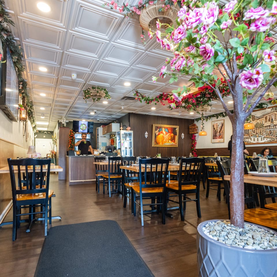 Vibrant restaurant interior with floral decor, dining tables, a counter, and seated customers.